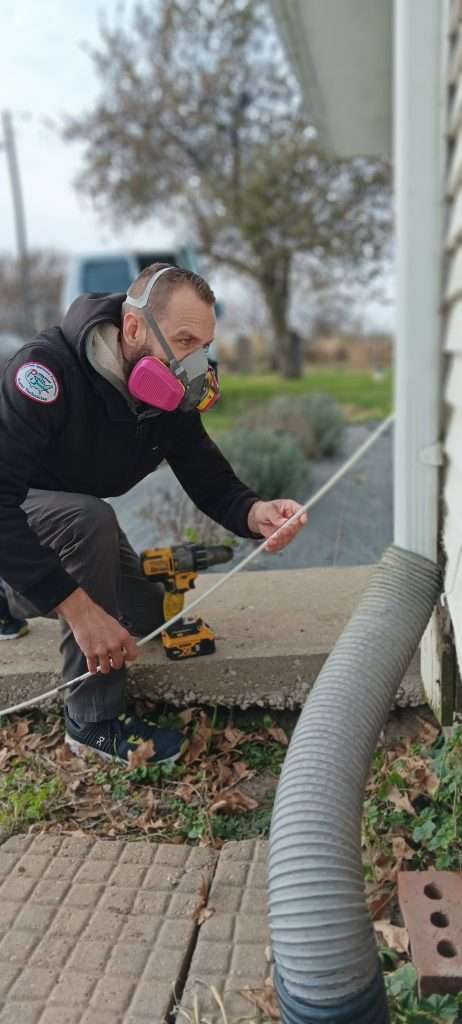 Dan feeding the dryer vent cleaning kit rod into the vent of the home.