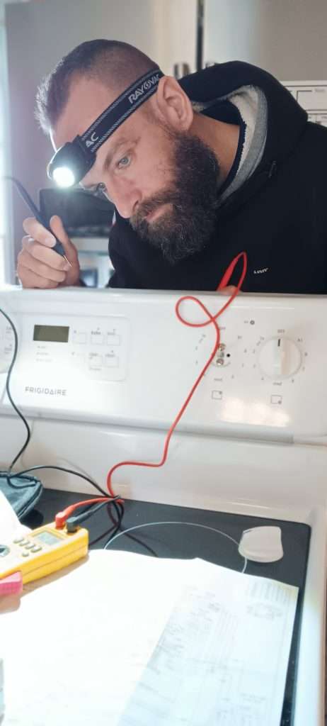 Dan reading the schematics working on an oven/range in Iowa.